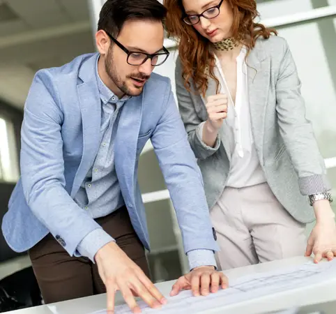 Dos profesionales revisan y discuten planos sobre una mesa