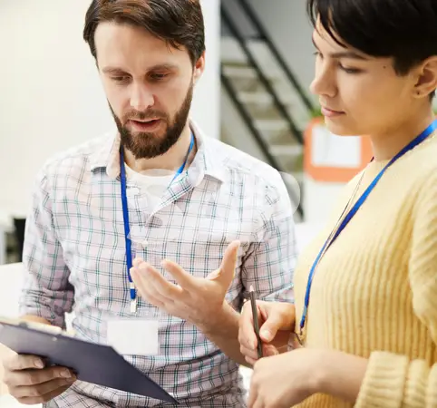 Dos personas con gafetes viendo información en una tablet.